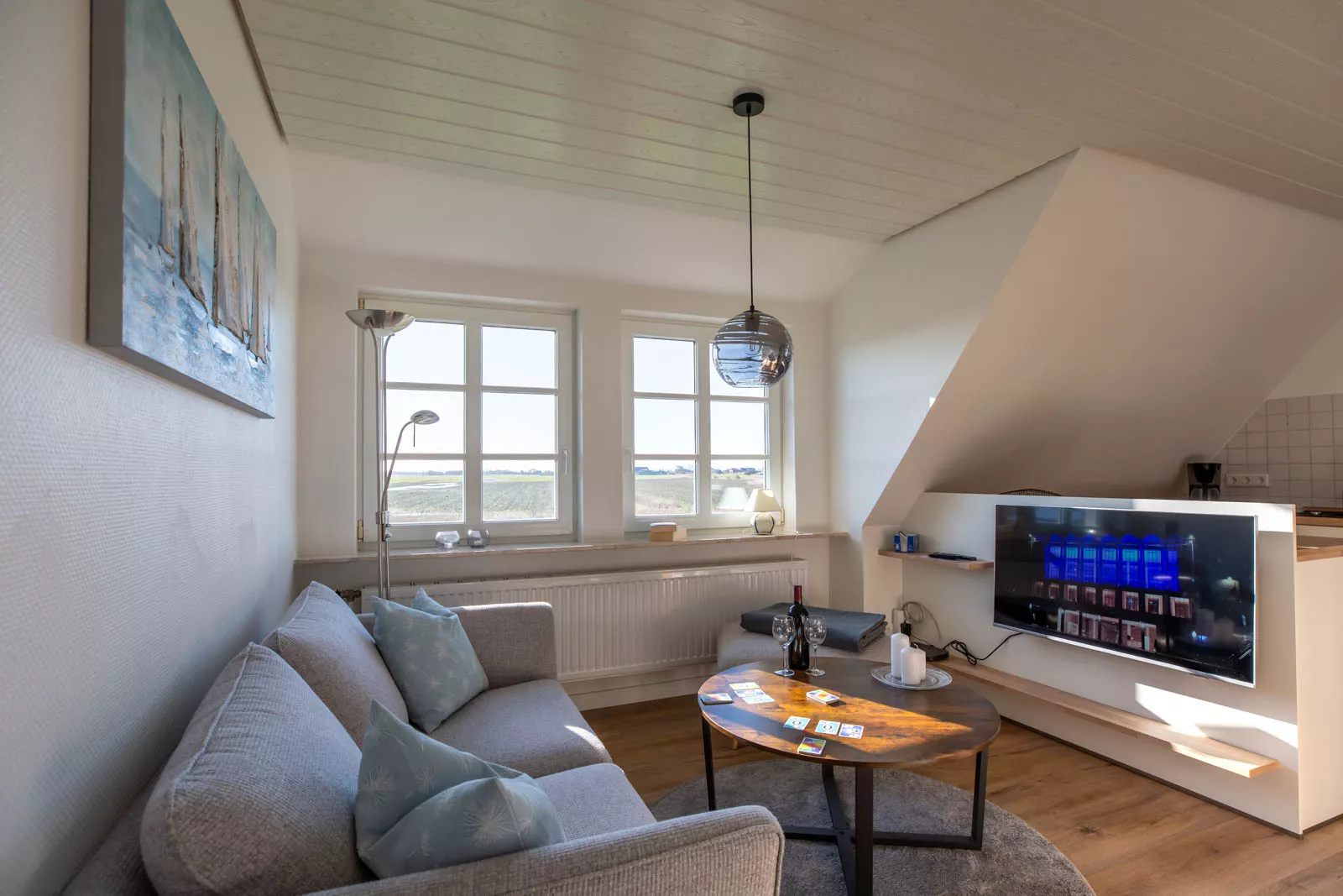 Gemütliche Couchecke mit großem Fenster und Fernseher in der Ferienwohnung auf Pellworm