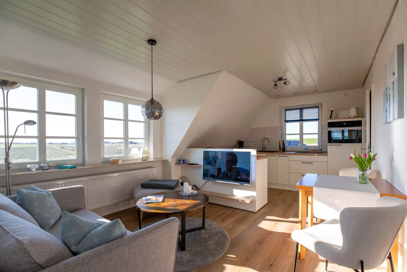 Heller Wohnraum der Ferienwohnung auf Pellworm mit Couchecke, Essplatz und offener Küche