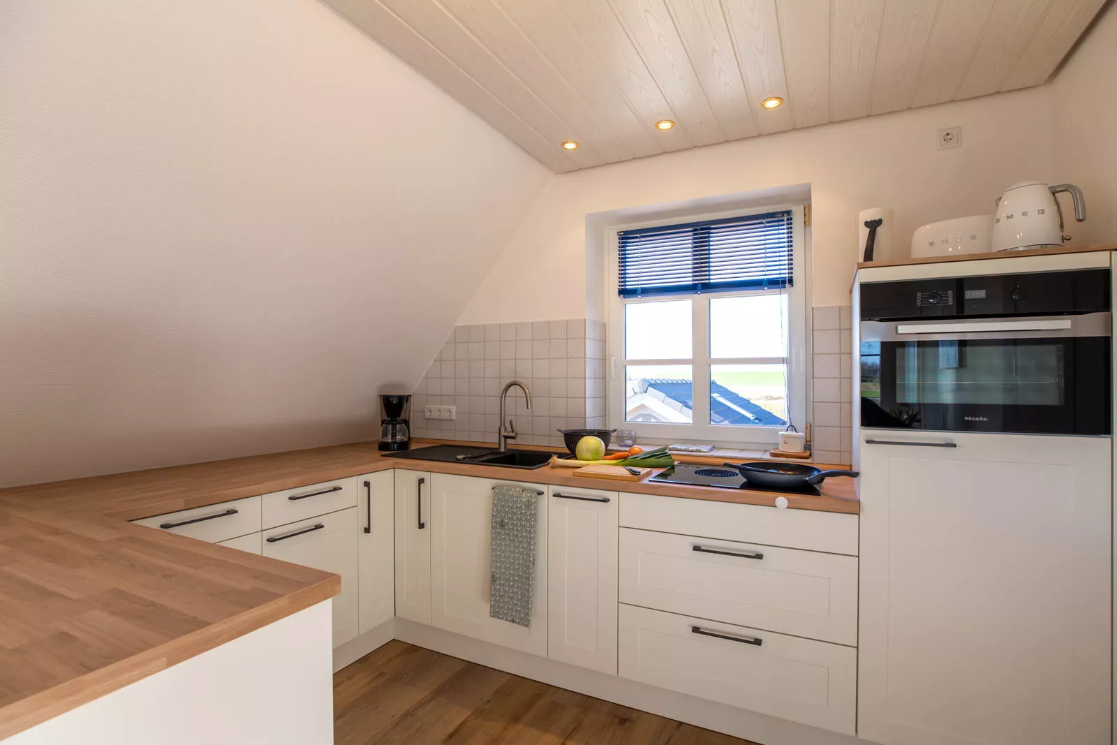 Moderne Küche der Ferienwohnung mit frischem Gemüse und Kochutensilien auf Pellworm